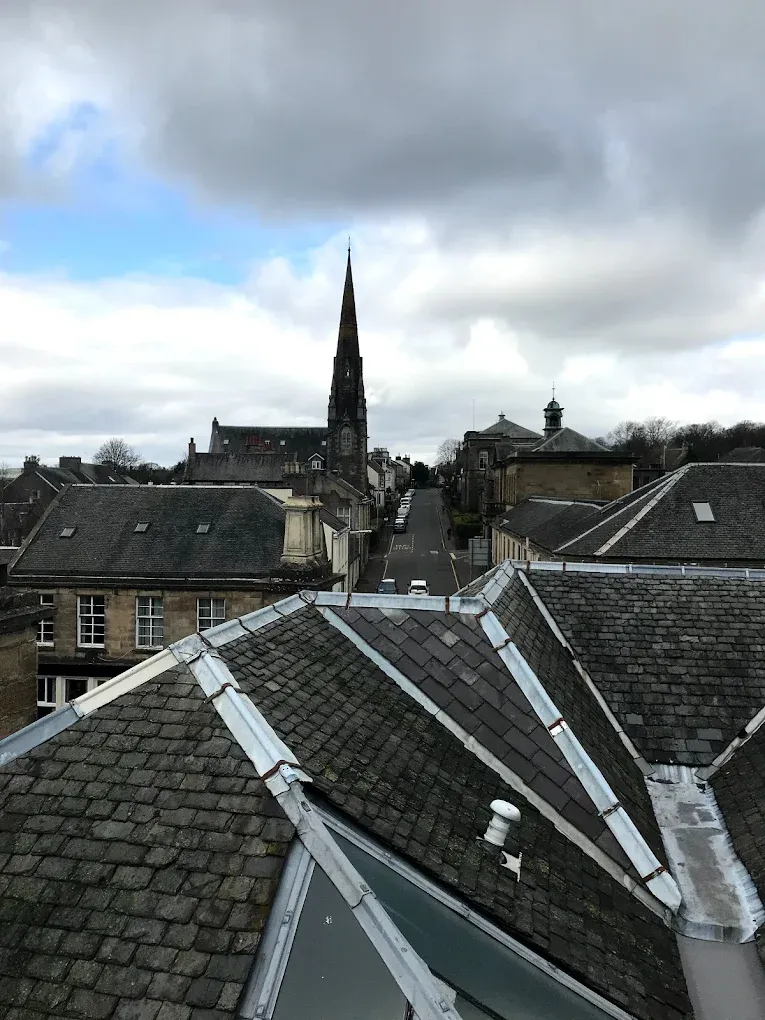 Traditional slate roofing in Lanark featuring a church spire in the background