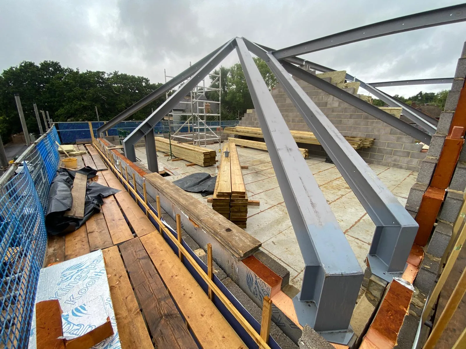 A complex structural steel roof frame installed on a residential construction site, demonstrating certified steel fabrication.