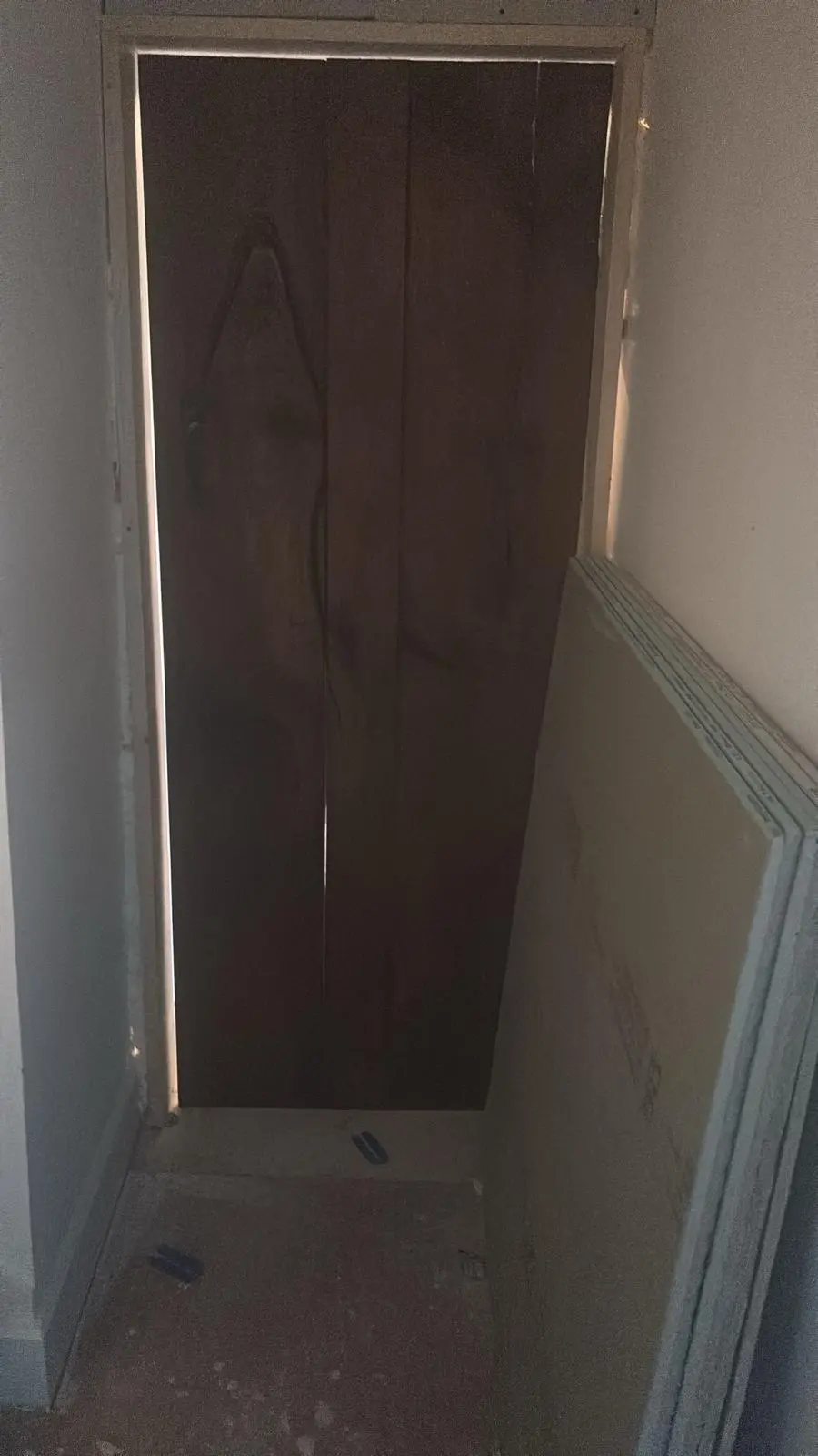 A solid wooden door partially installed in a door frame with plasterboard nearby, representing renovation and joinery work in progress by Fortura Construction LTD.