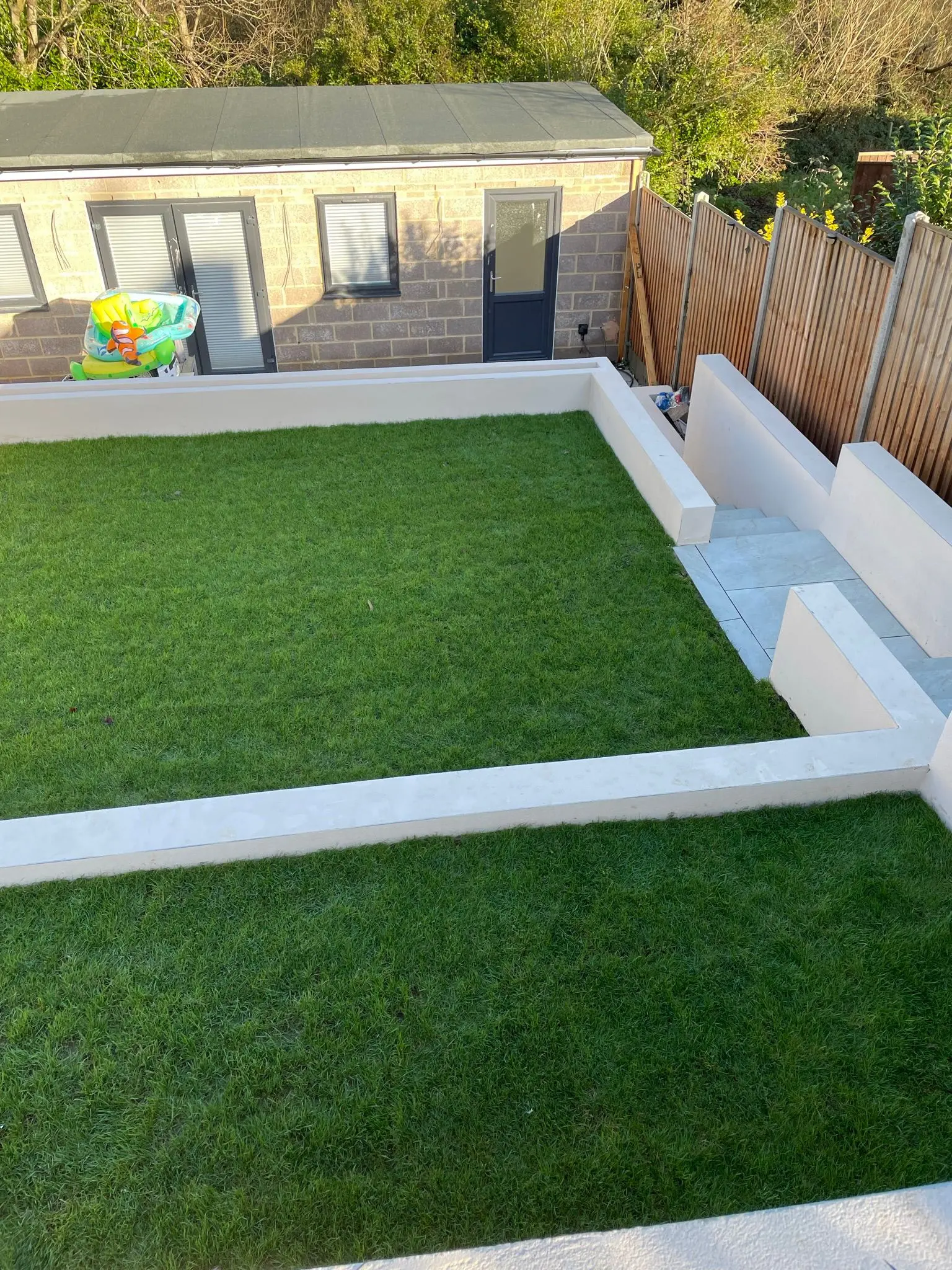 Aline Construction completed garden landscaping project showing tiered retaining walls and a manicured lawn.