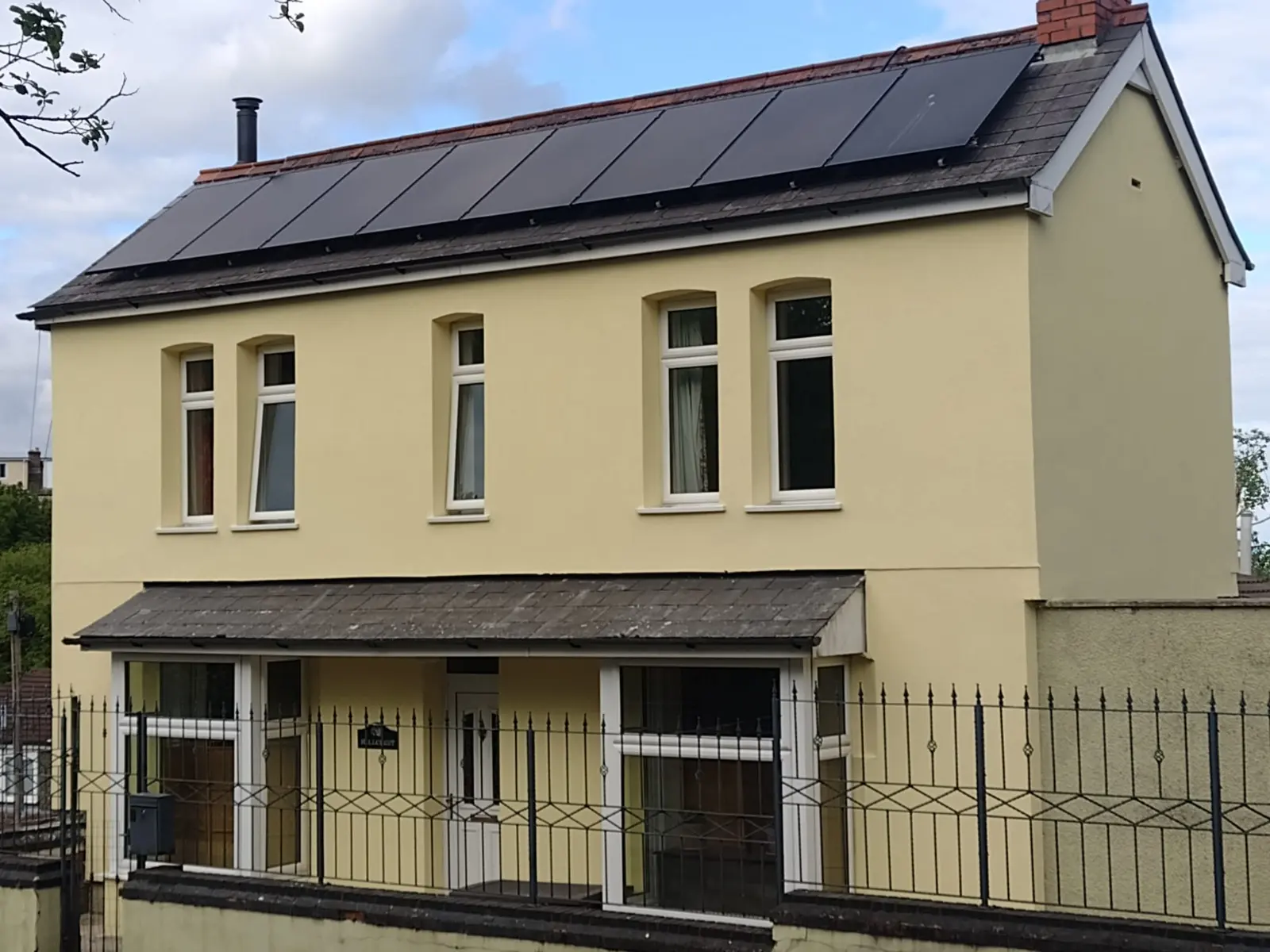A detached house in South Wales showcasing a new yellow silicone render finish and external wall insulation installation.