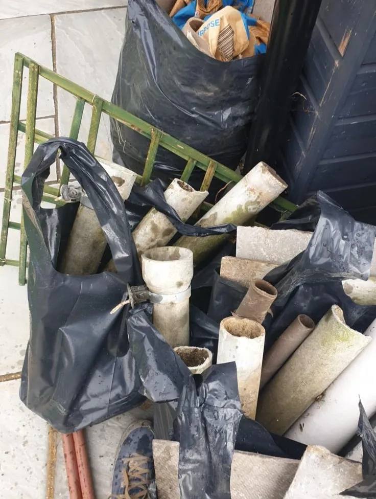 Asbestos cement pipes and materials being placed in black bags for safe disposal by Stay Safe Environmental.