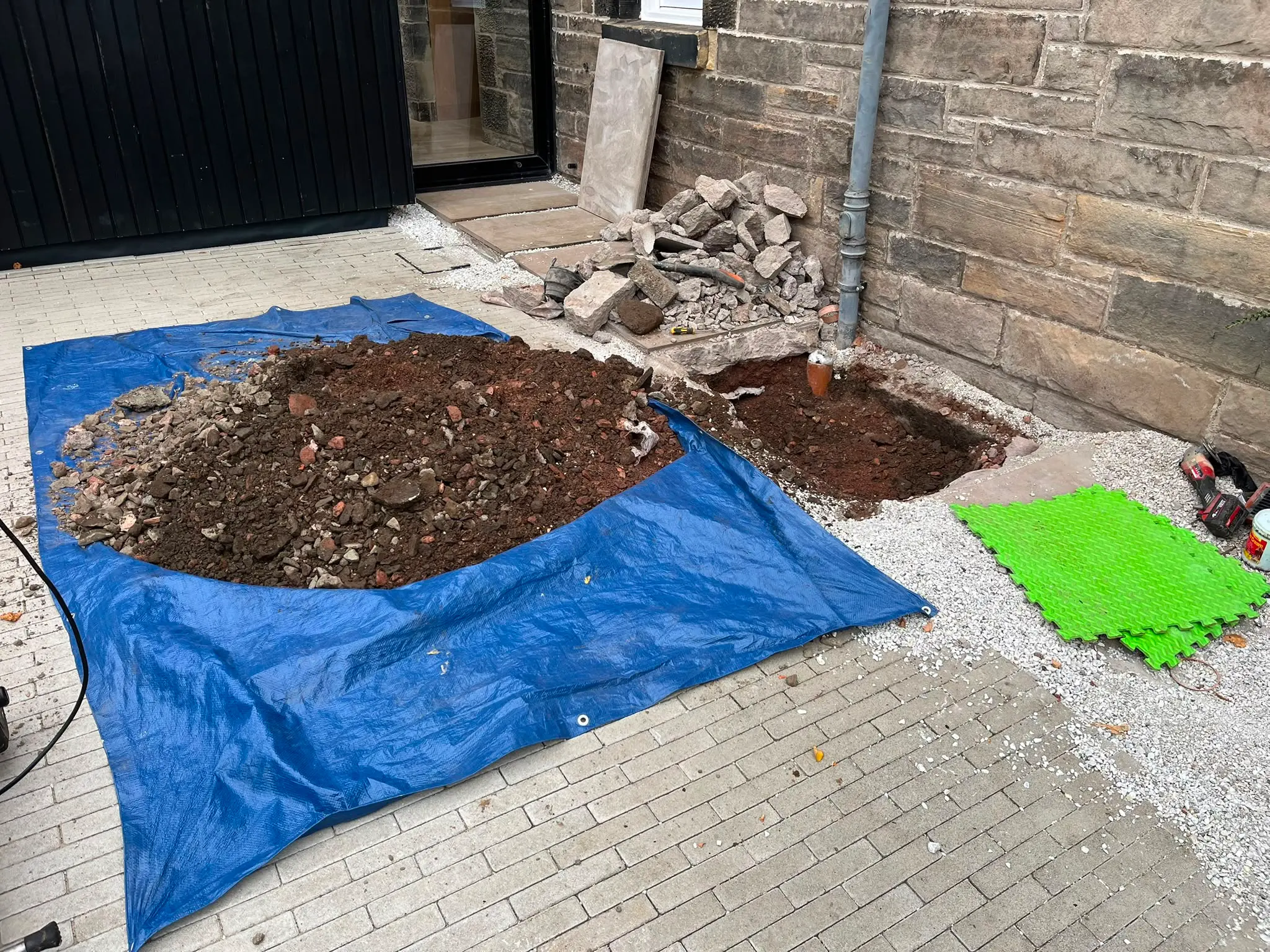 Careful drainage excavation and groundworks in Clackmannanshire by CB Drainage, demonstrating respect for customer property by protecting the patio.