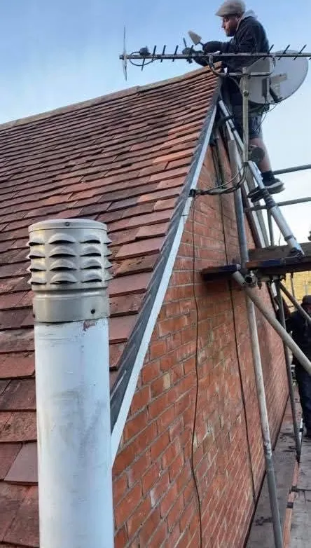 A roofer performing repairs on a pitched tiled roof in Hampshire