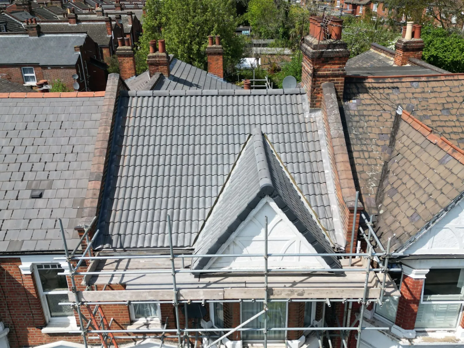 Newly installed grey tiled roof on a house with scaffolding.