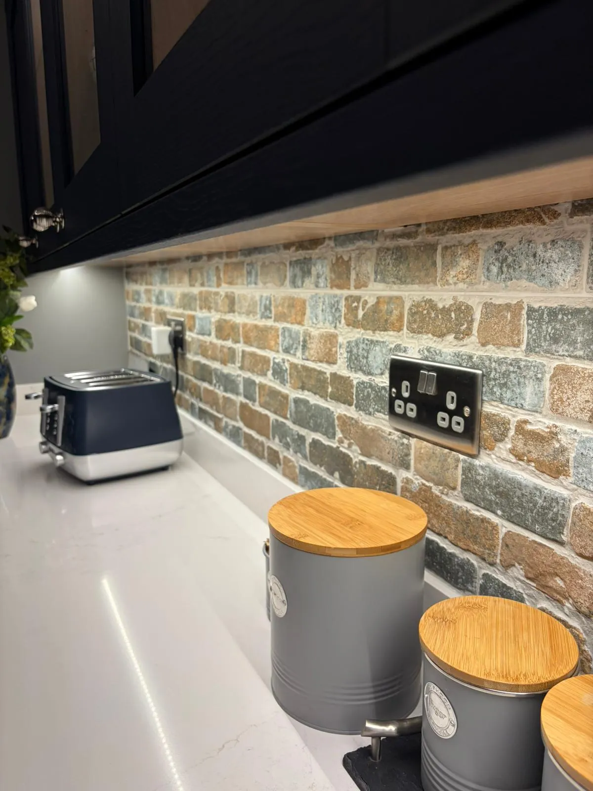 High-quality kitchen fitting and electrical installation in Felixstowe featuring a brick slip splashback and modern sockets by FLEX PROPERTY SERVICES.