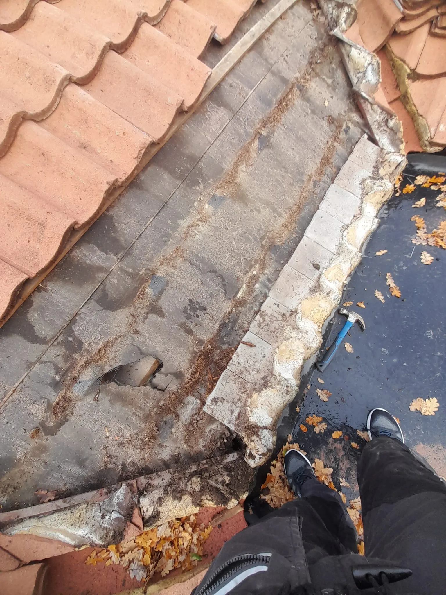 Close-up of damaged roof tiles and felt being inspected for repairs