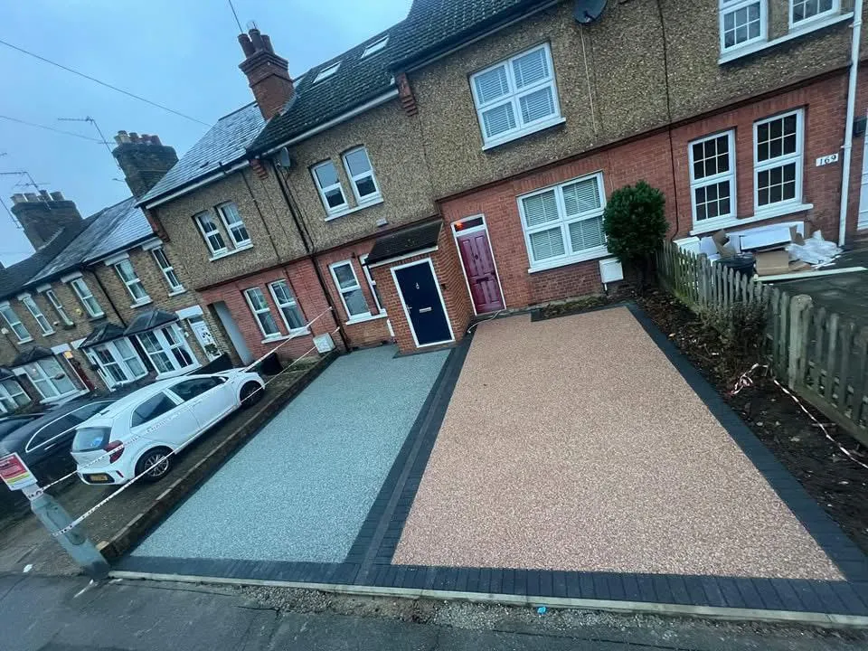 Two newly installed resin bound driveways in different colours with block paving edging in front of terraced houses.