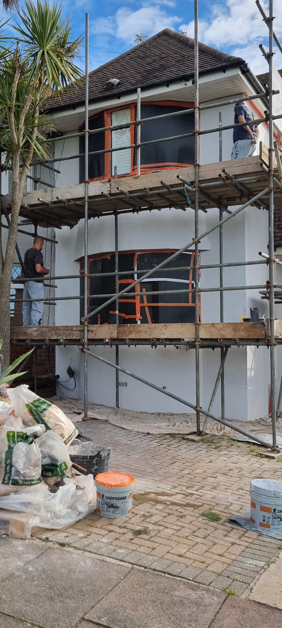 Professional external rendering project in progress on a house in Southwick with scaffolding and workers.