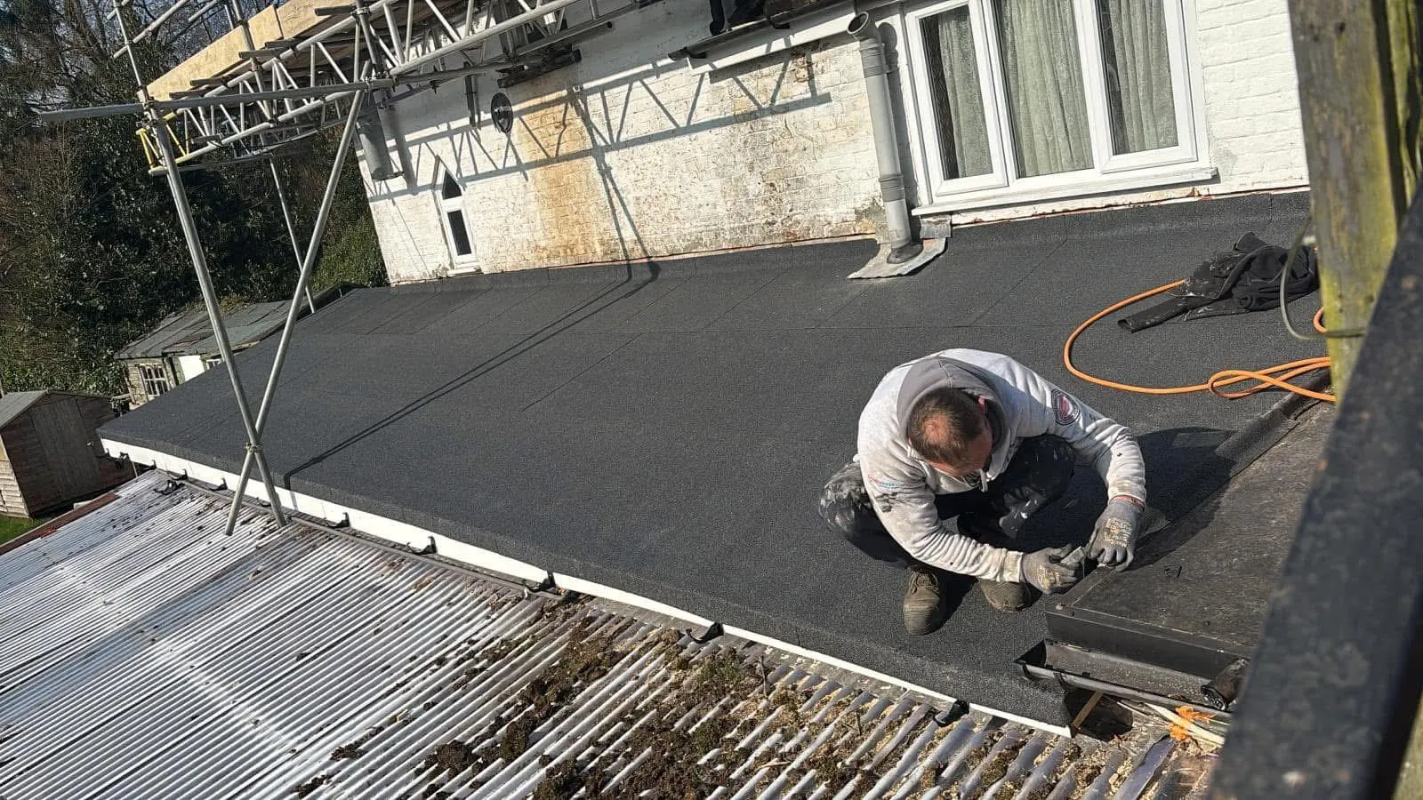 Expert roofer from HomeGuard Roofing Ltd installing a new high-performance flat roof membrane or performing flat roof repair on a property in East Sussex.