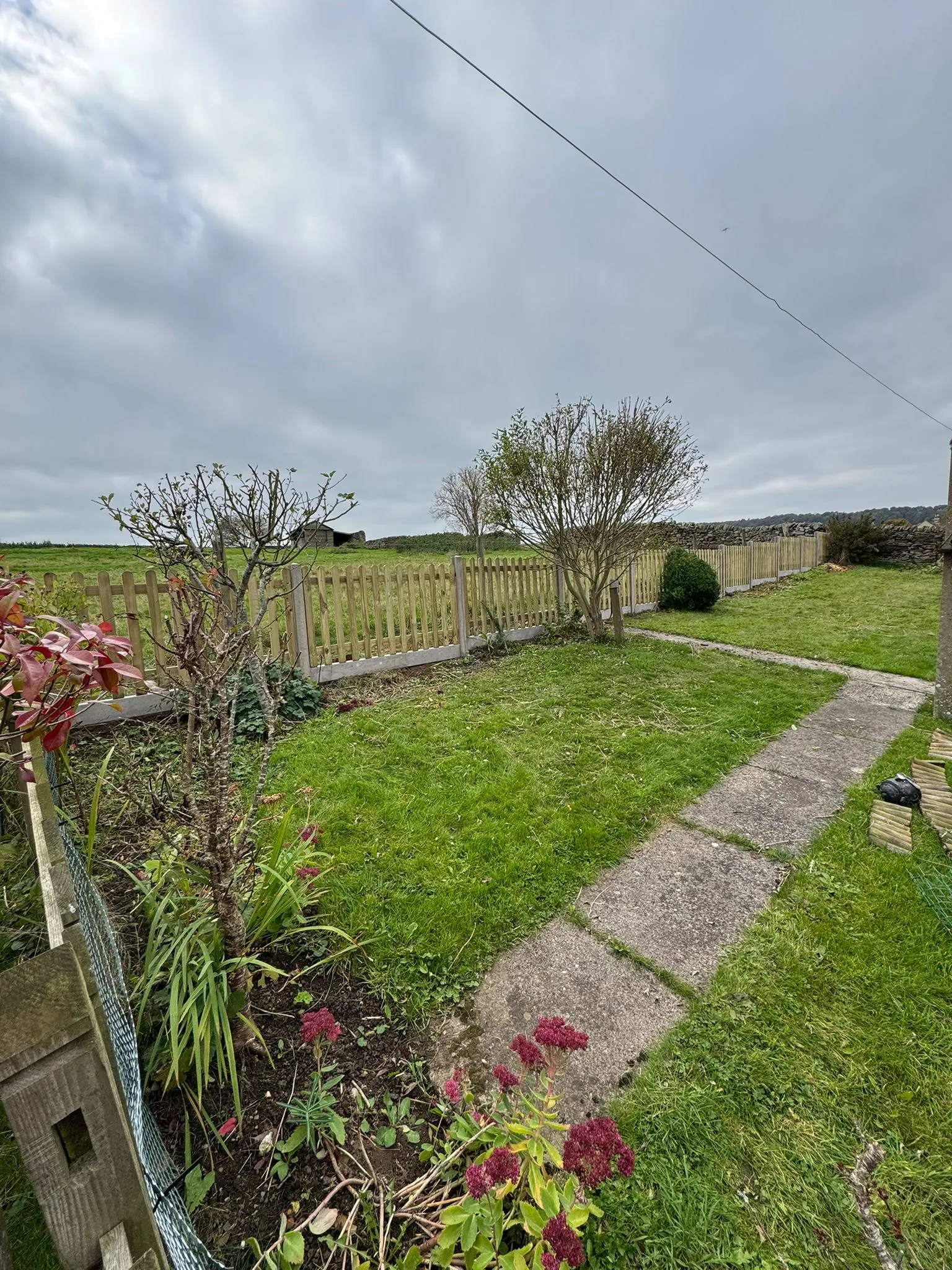 New wooden picket fence installation in a Leicestershire garden by Woodscapes, featuring a lawn and path.