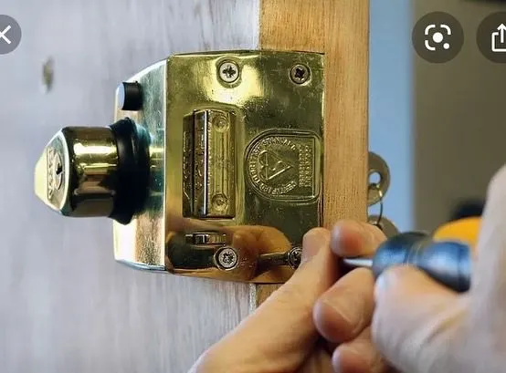 Locksmith adjusting or installing an insurance-approved British Standard (BS3621) night latch lock on a wooden door.