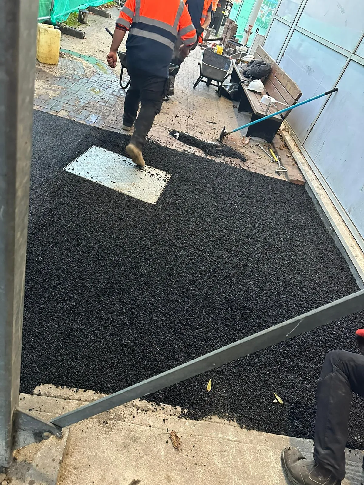Professional civils and groundworks team laying fresh asphalt around a manhole cover in Cambridgeshire.