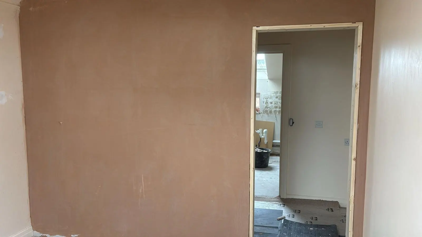 Freshly plastered wall and new wooden door frame during a residential interior renovation.