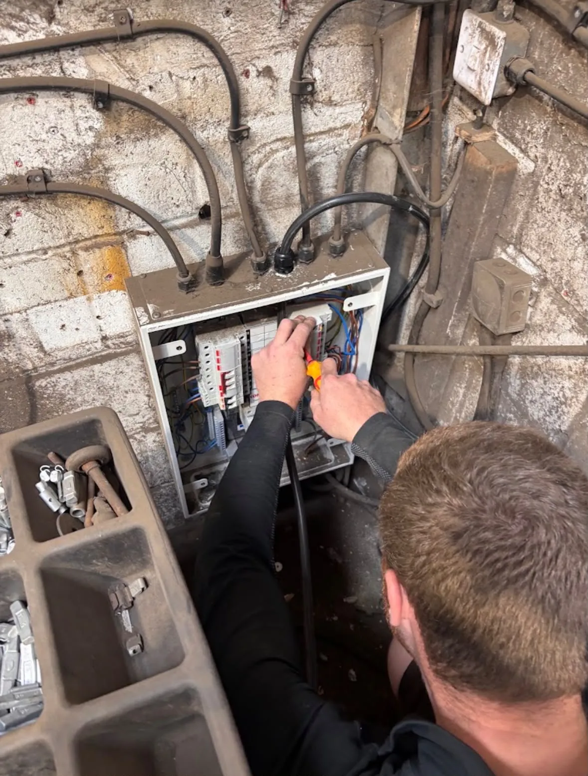 Electrician installing and wiring a consumer unit distribution board