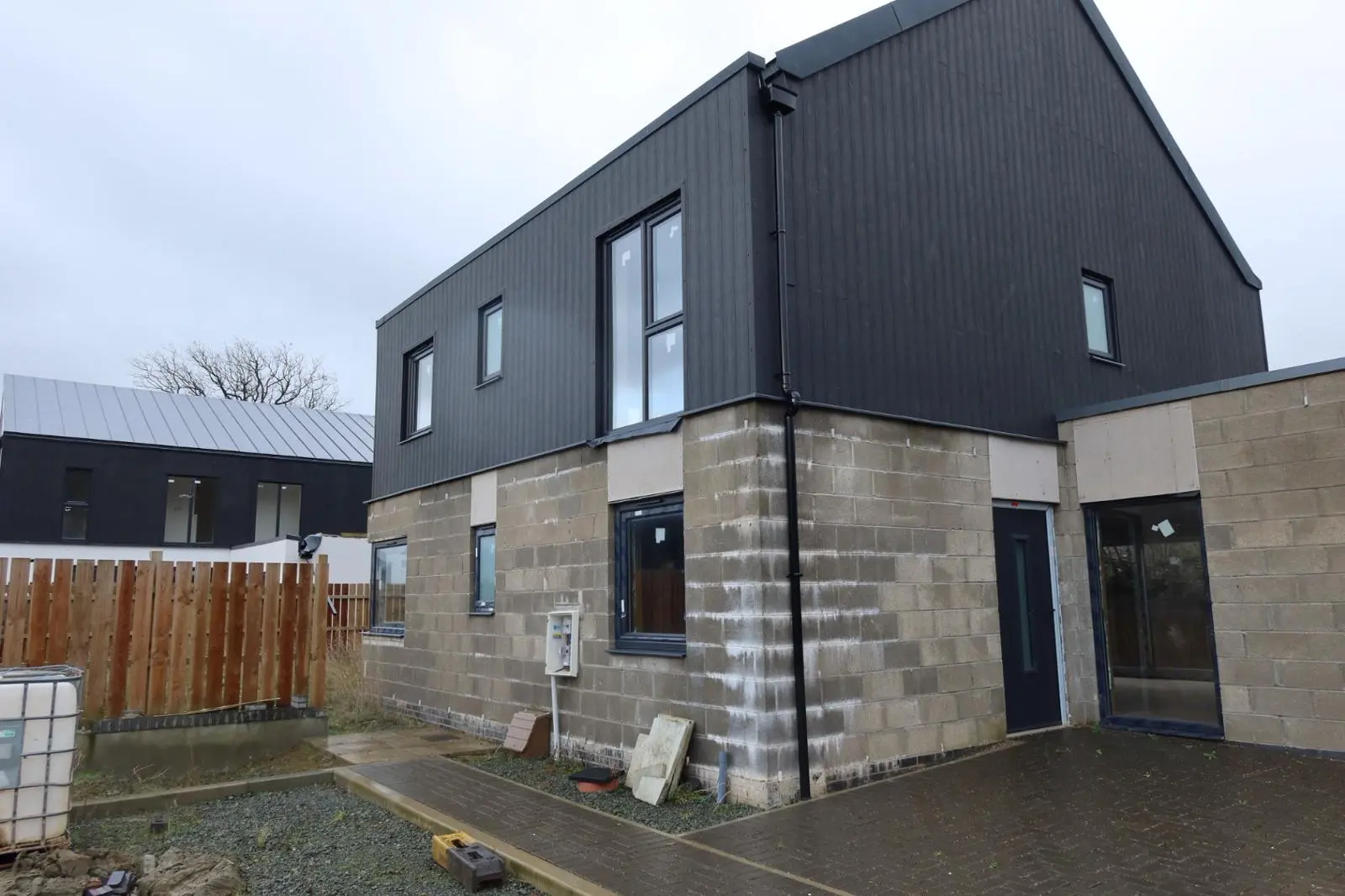 Modern new build property with exposed concrete blockwork on the lower level awaiting external rendering or insulation
