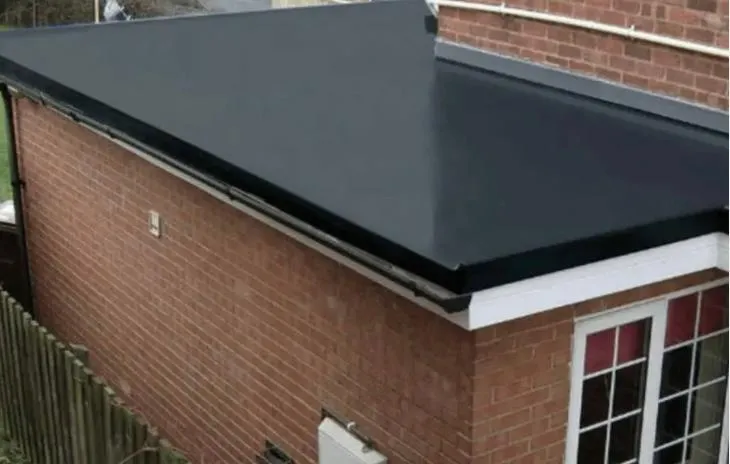 A modern dark flat roof on a brick extension or garage, with white fascias and guttering.