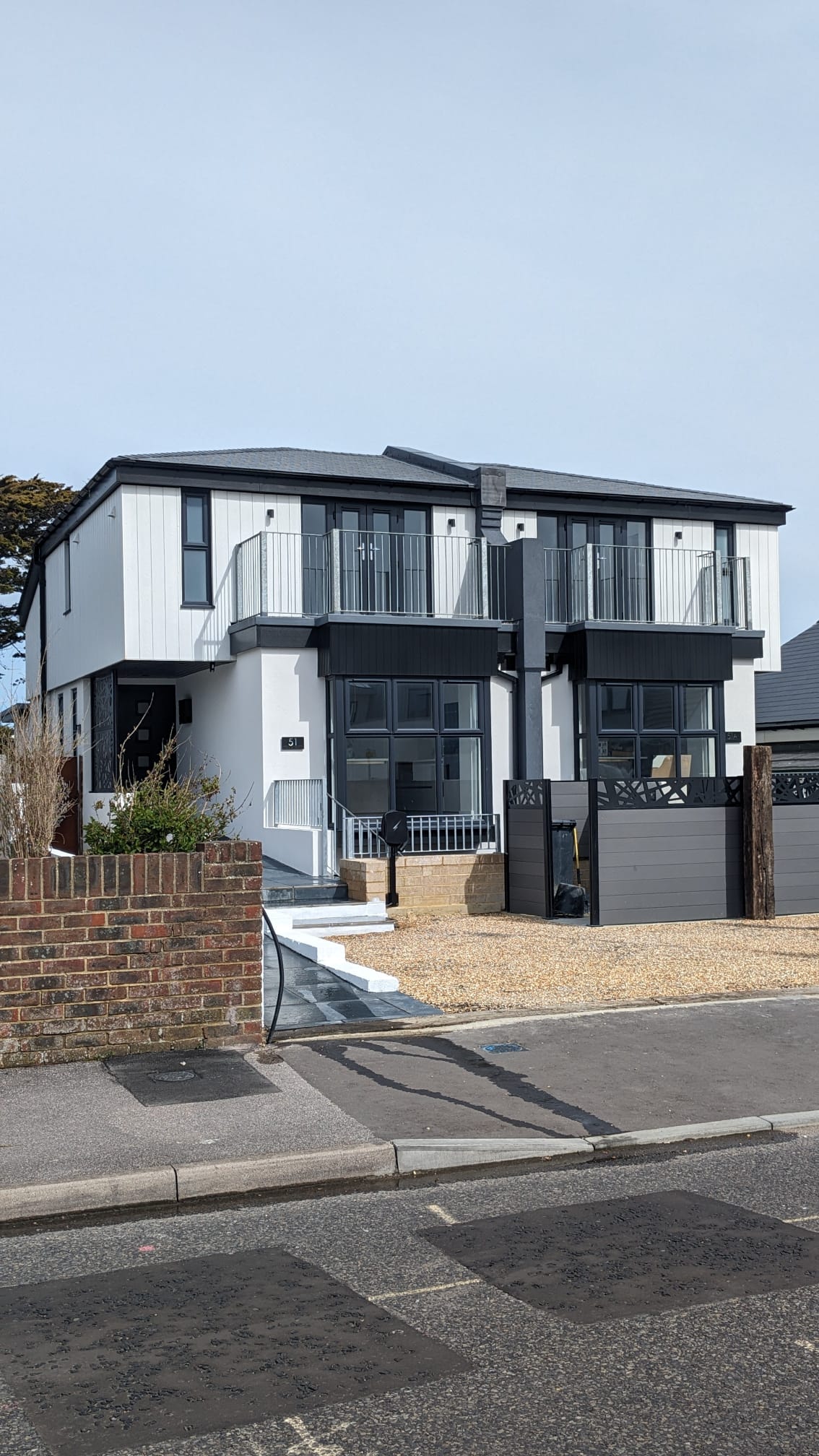Modern residential building with professional white external rendering and black architectural details.