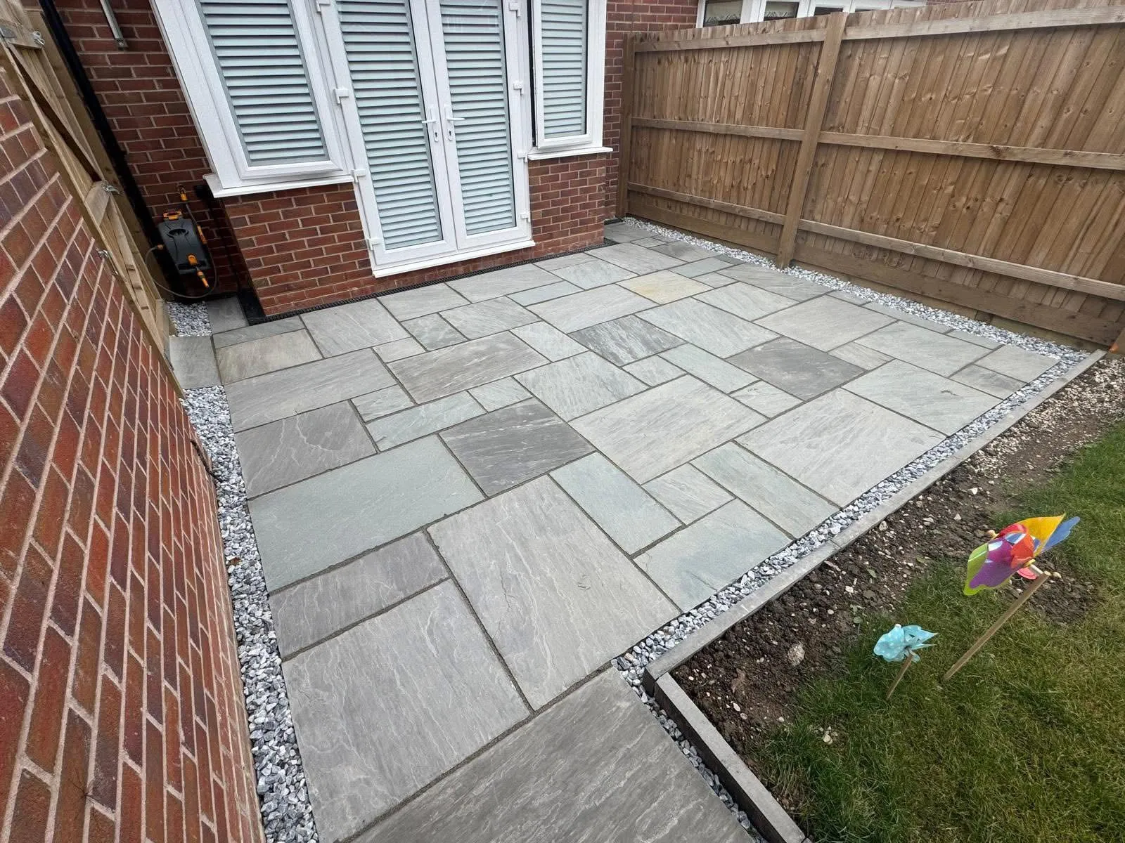 Grey Indian sandstone patio slabs with gravel border installed by Kent Paving & Resin LTD