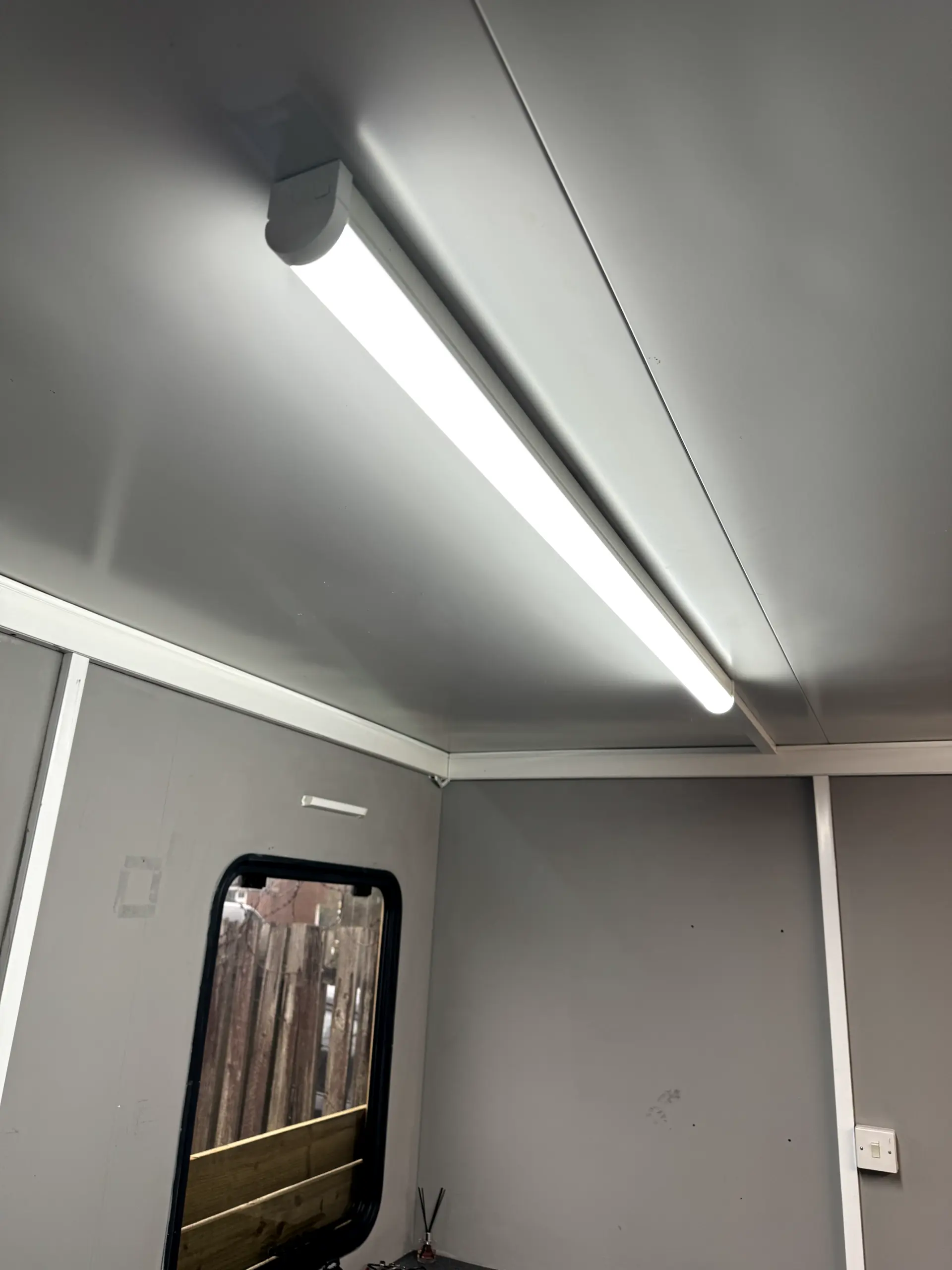 A modern LED strip light fixture installed on a paneled ceiling