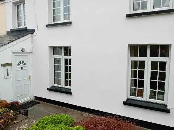 A picture of a white terraced house with newly applied external render