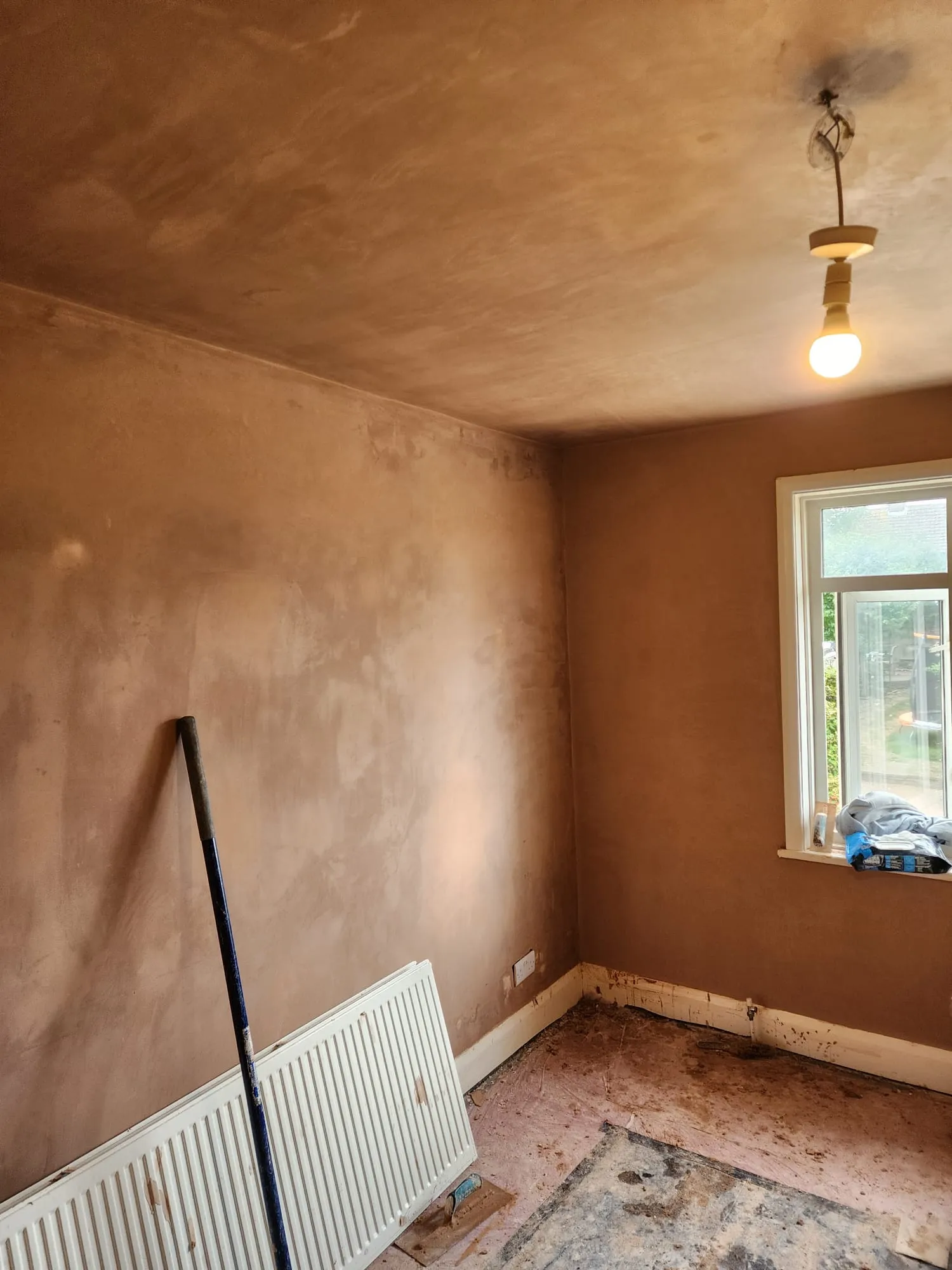 Freshly plastered and skimmed walls and ceiling in a residential room renovation.