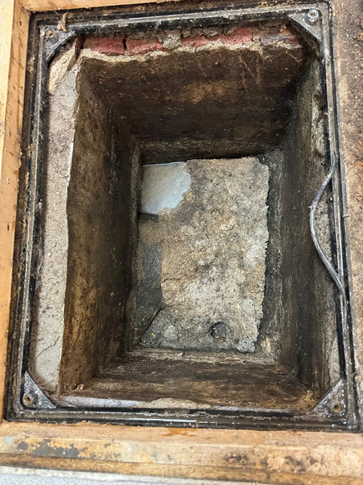 A picture of a heavily blocked external drain filled with fat and debris.