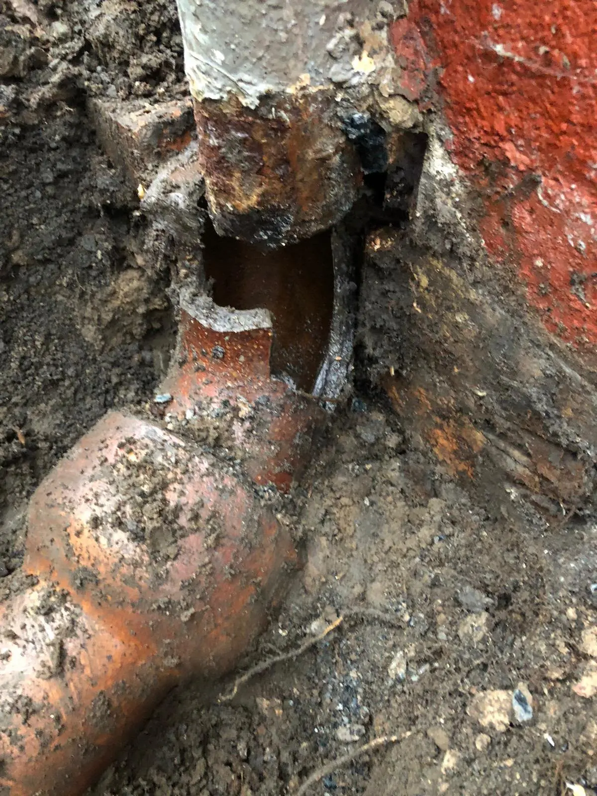 An excavated broken underground drain pipe with severe structural damage, requiring collapsed drain repair or replacement