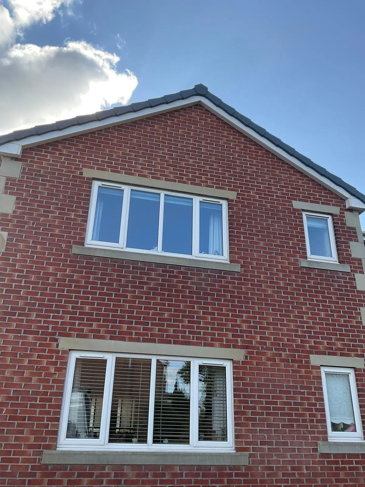 A modern red brick house with a newly completed pitched tile roof