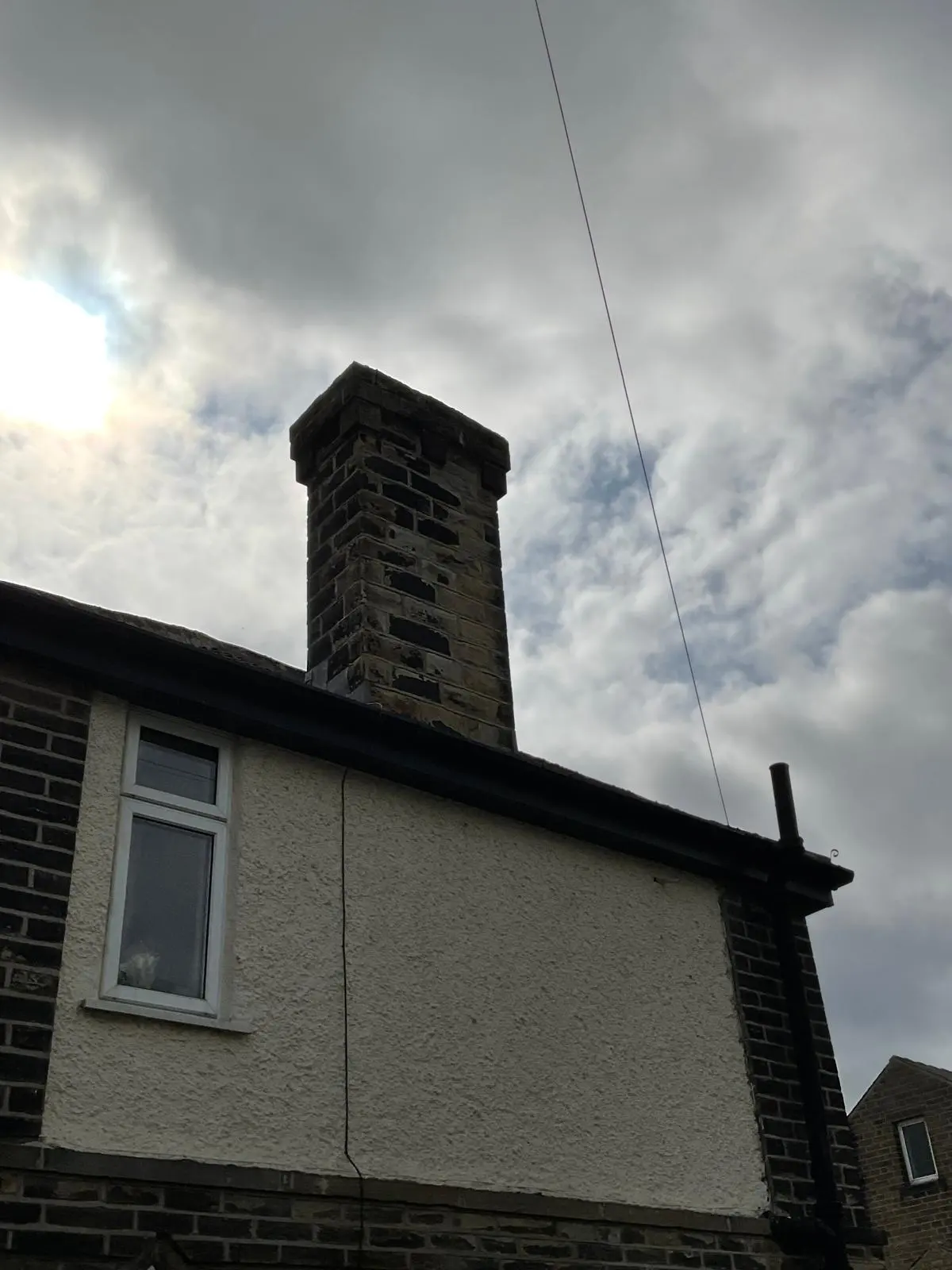 Traditional brick and stone chimney stack on a residential property requiring repointing or repairs