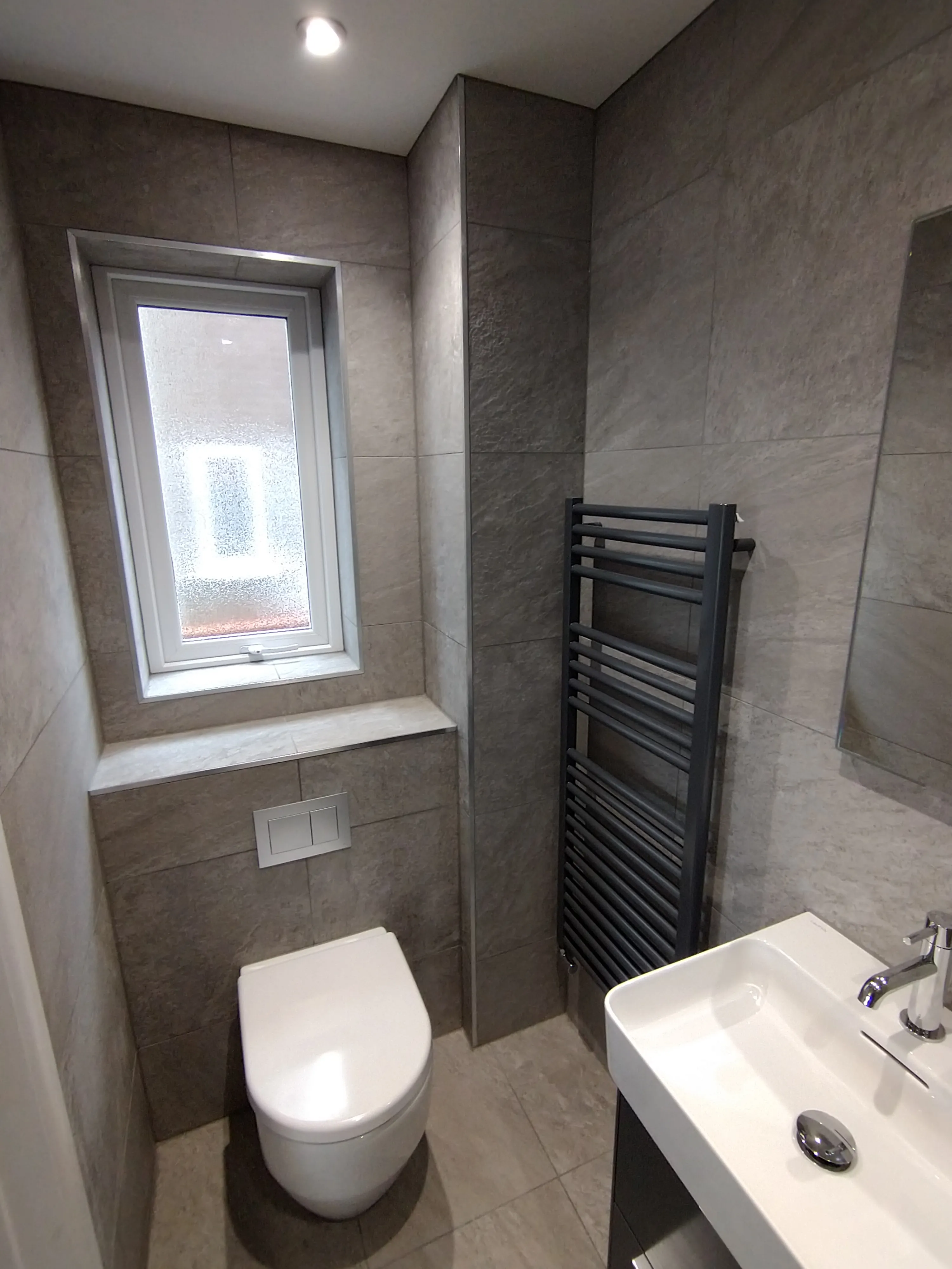 Bespoke luxury cloakroom installation in Plymouth featuring grey tiling and modern fixtures by Sands & Vossen.