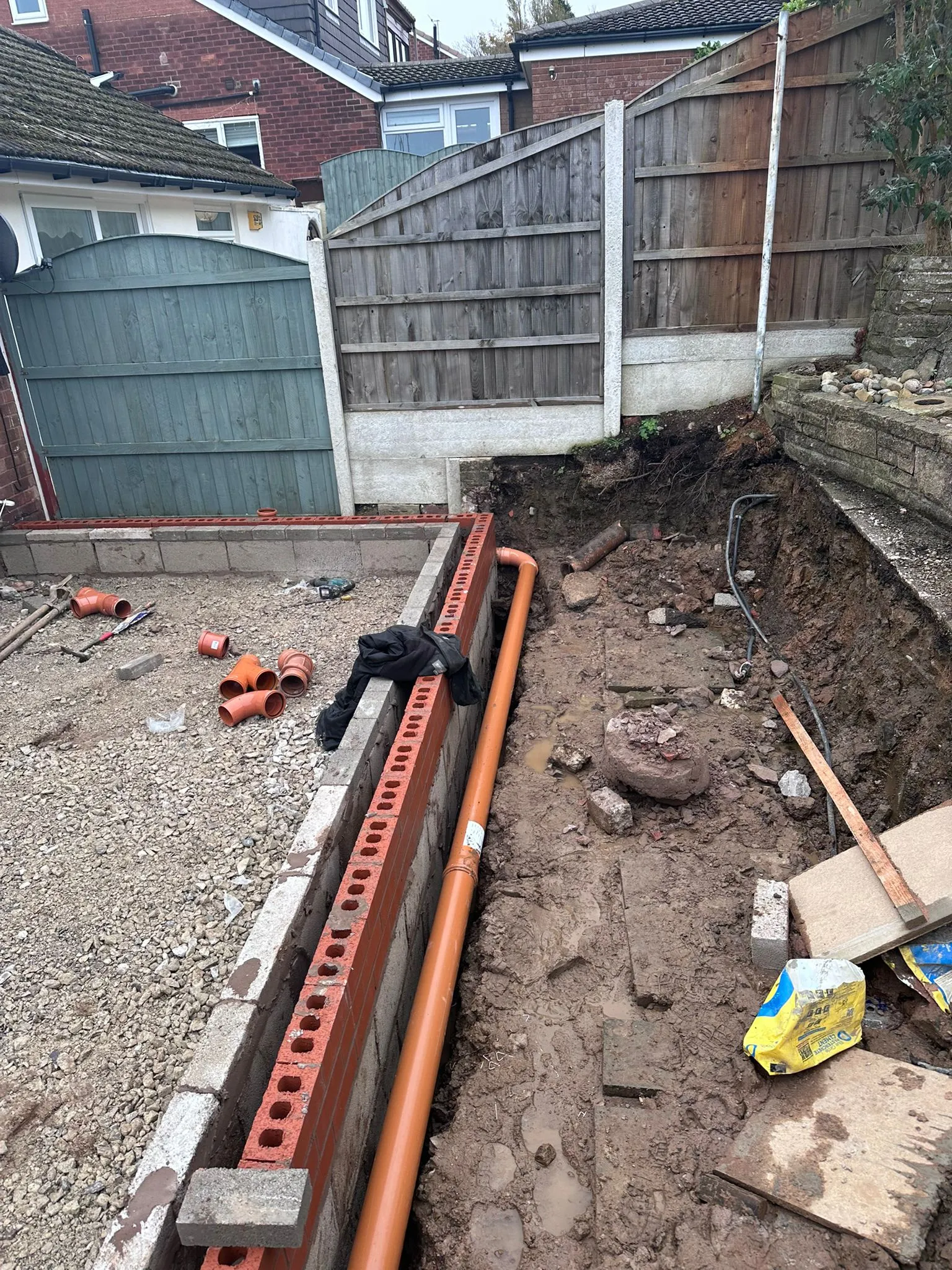 Drainage pipe installation and excavation repair in a residential garden.