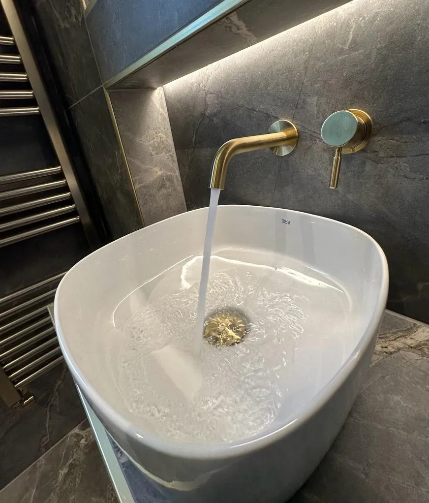 High-end bespoke bathroom design in Plymouth showing a white vessel sink and brushed brass wall tap by Sands & Vossen.