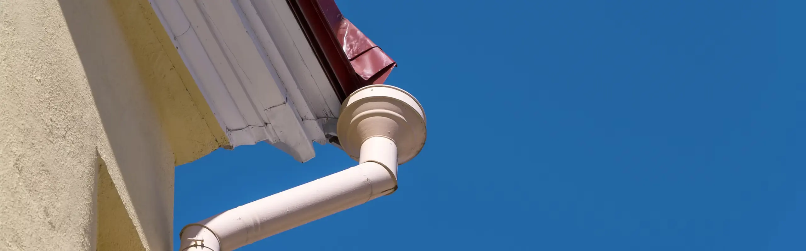 White guttering and downpipe against a blue sky