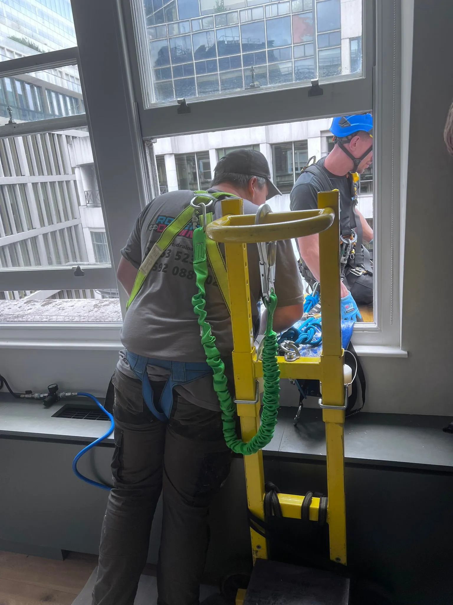 Roberts Drainage Ltd technicians in safety harnesses performing commercial drainage maintenance at height.