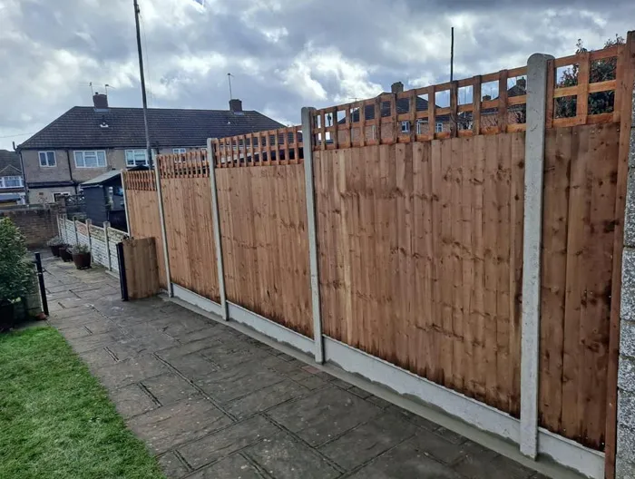 Newly installed wooden garden fence with concrete posts and gravel boards in a residential garden.