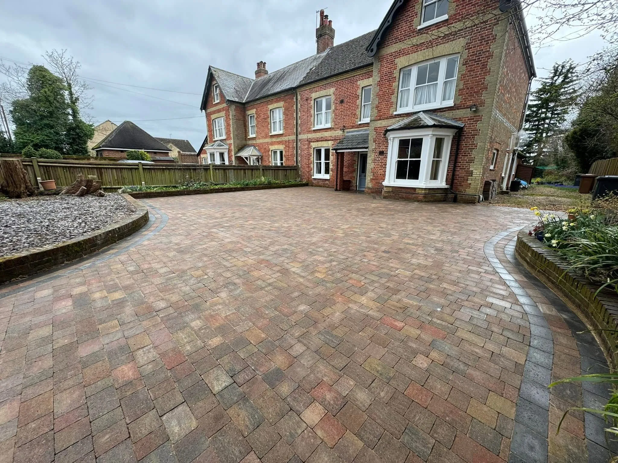 A professional block paving driveway installation with curved borders and dark grey edging in front of a period property.