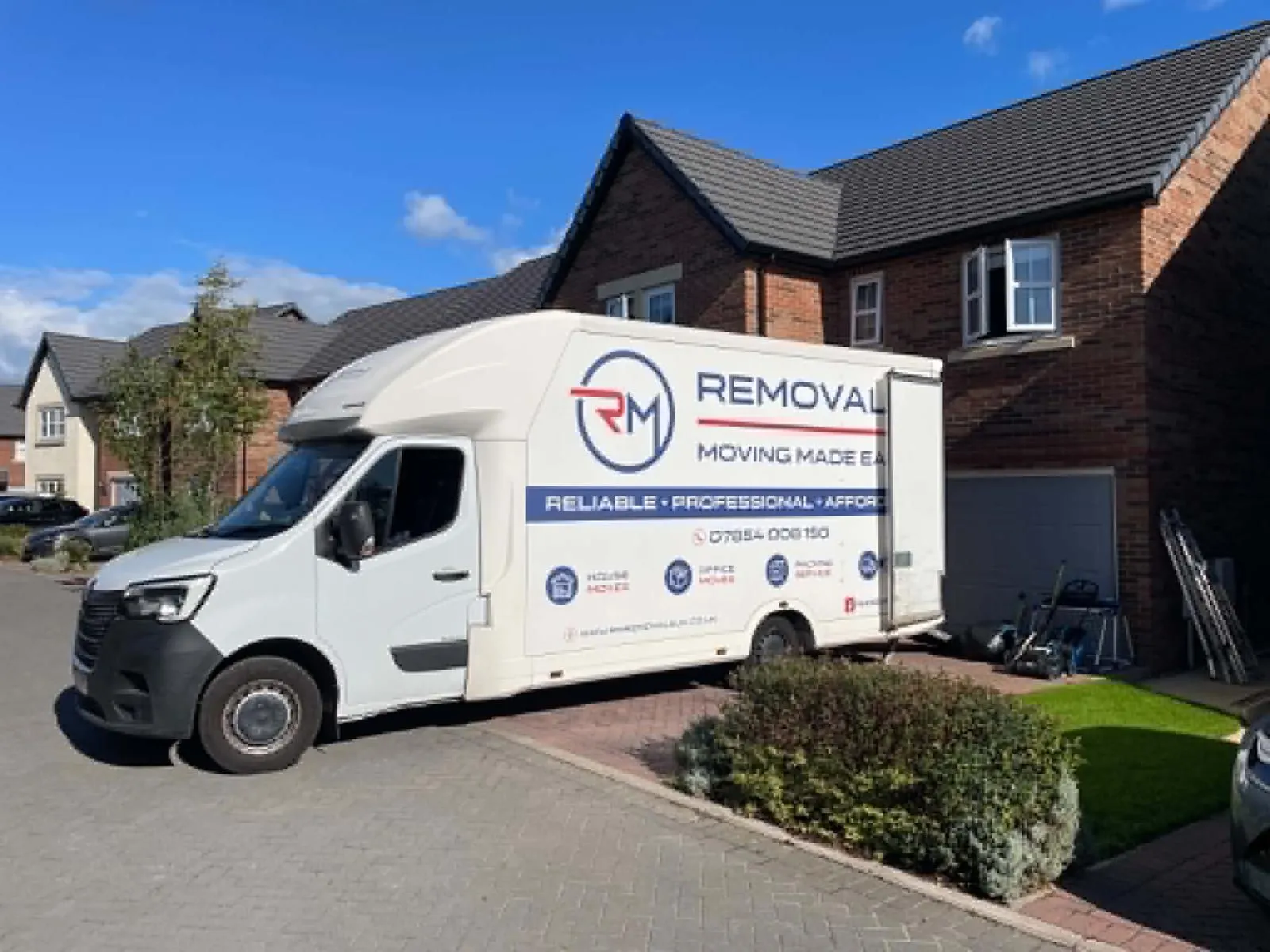 RM Removals van parked on a residential driveway outside a brick house