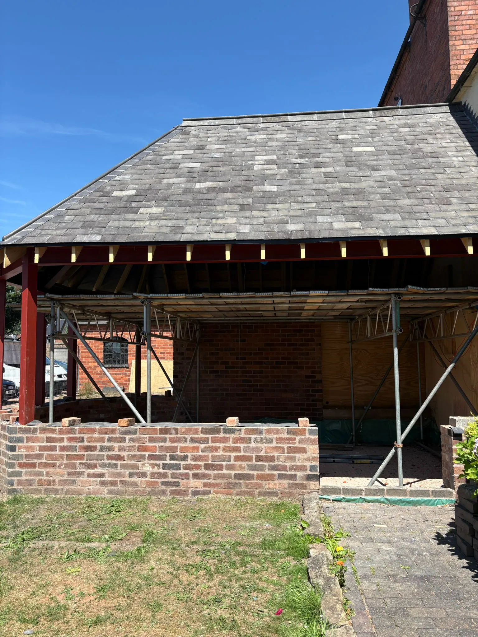 An unfinished home extension in the West Midlands with a new roof structure and scaffolding.