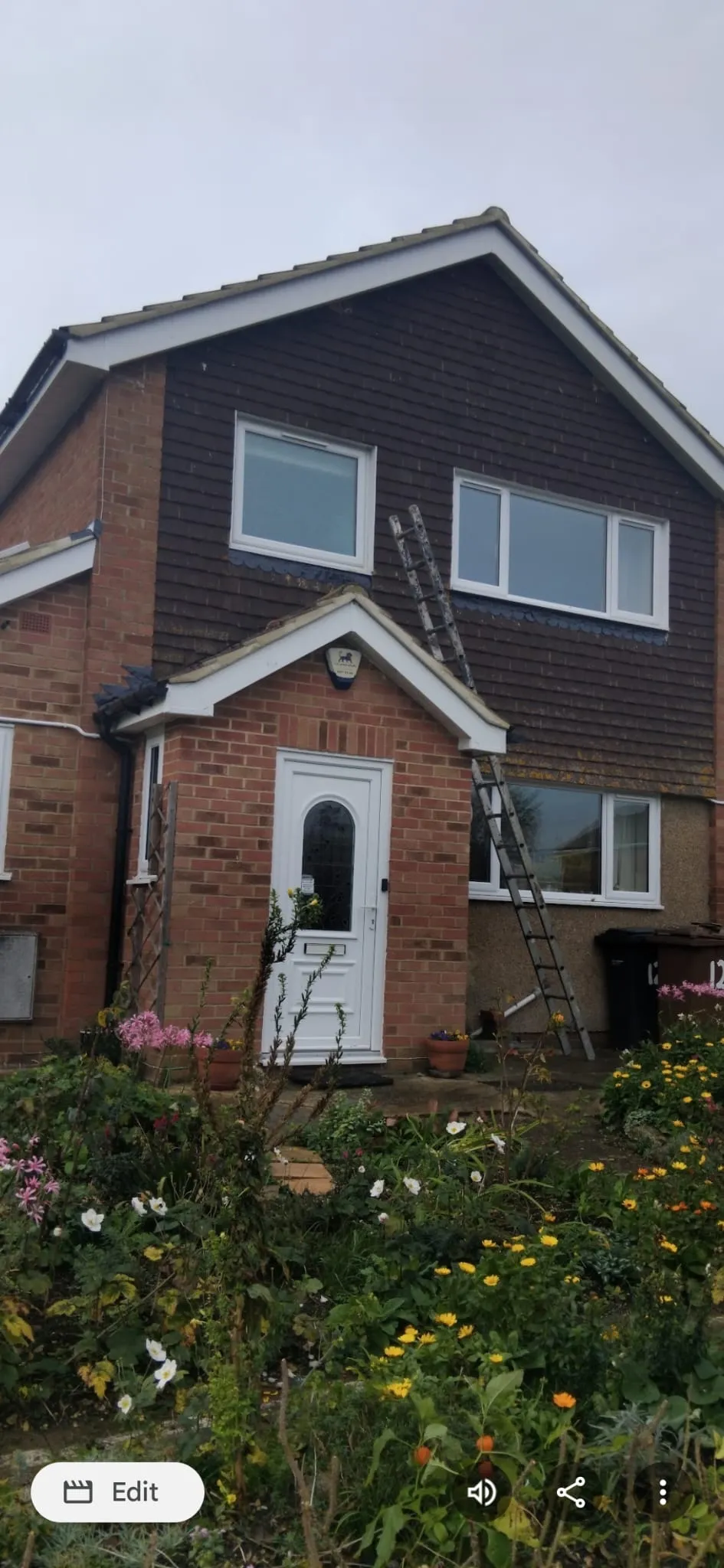 Residential property with access ladder set up for vertical tile hanging and tiled roof repair