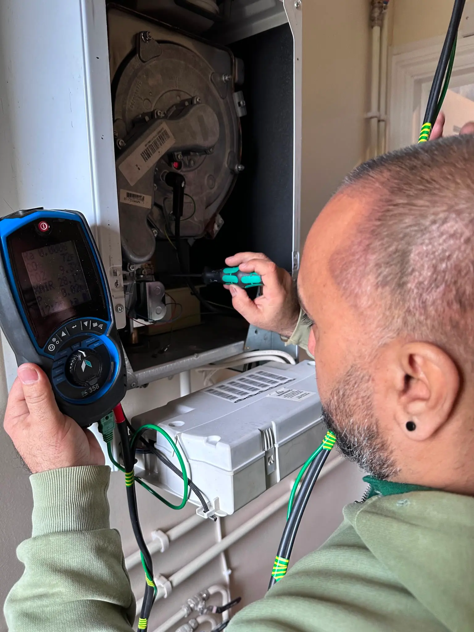 A Gas Safe registered engineer from JMA Plumbing & Heating performing a professional boiler service using a digital flue gas analyzer.