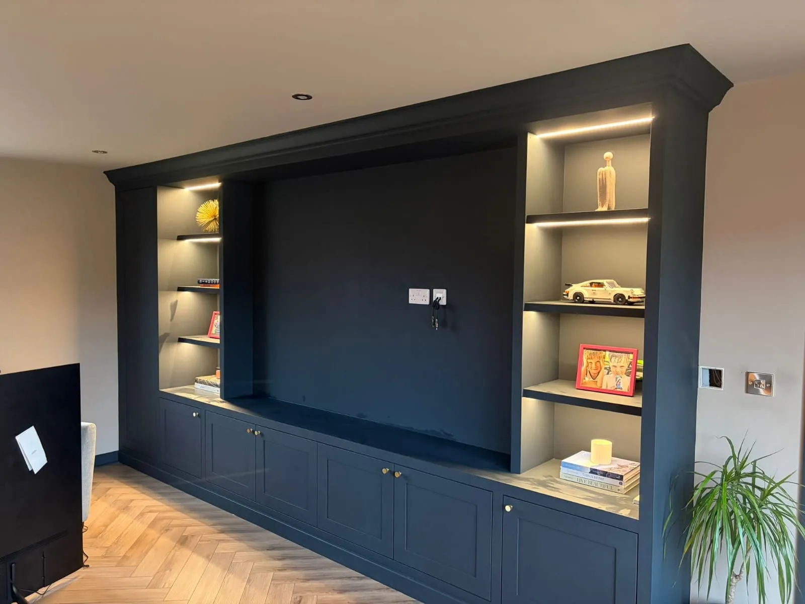 Bespoke navy blue media unit with integrated lighting and custom joinery by FLEX PROPERTY SERVICES in Felixstowe.