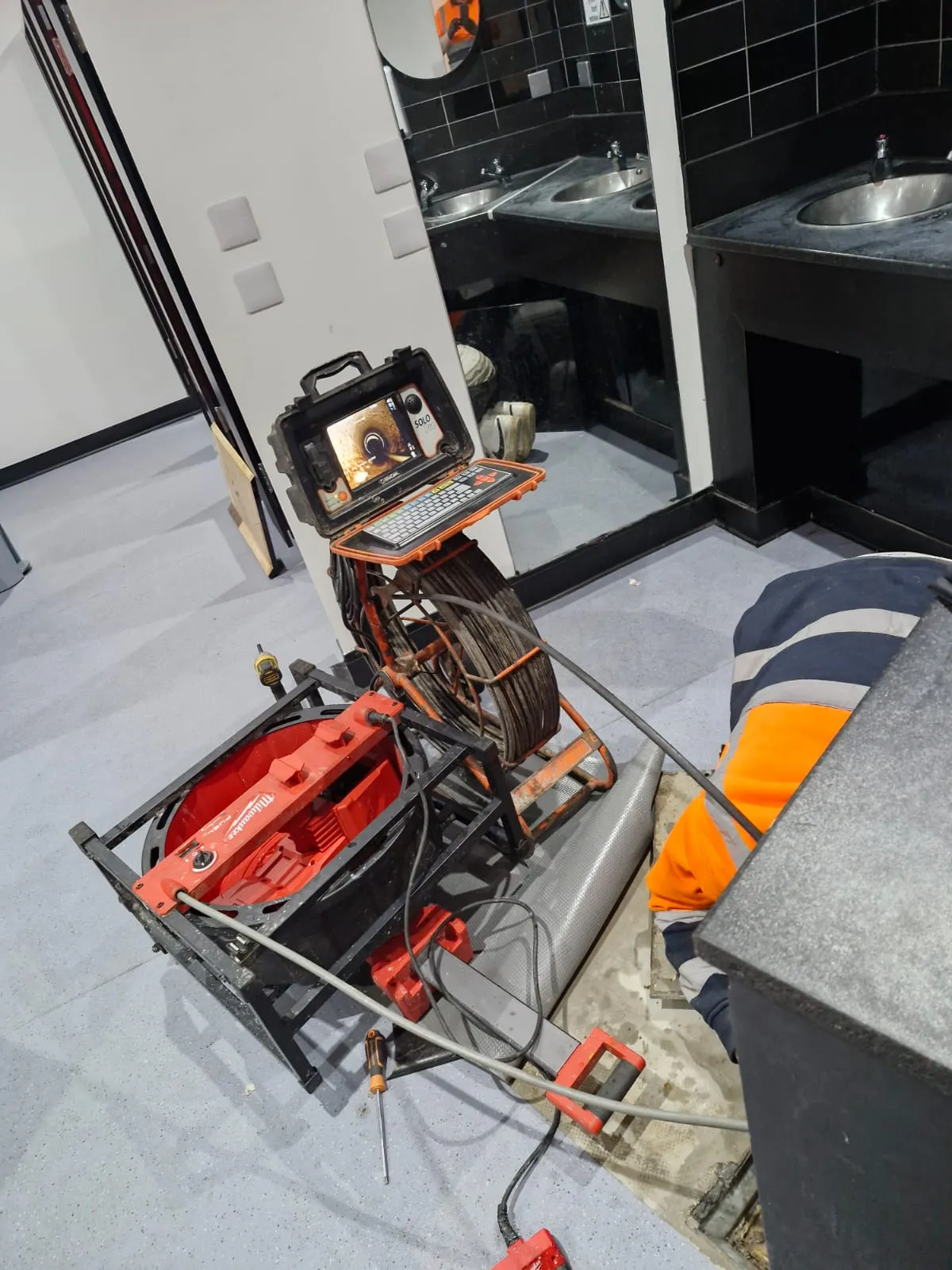 CCTV drain survey and cleaning equipment being used in a commercial restroom by Roberts Drainage Ltd.