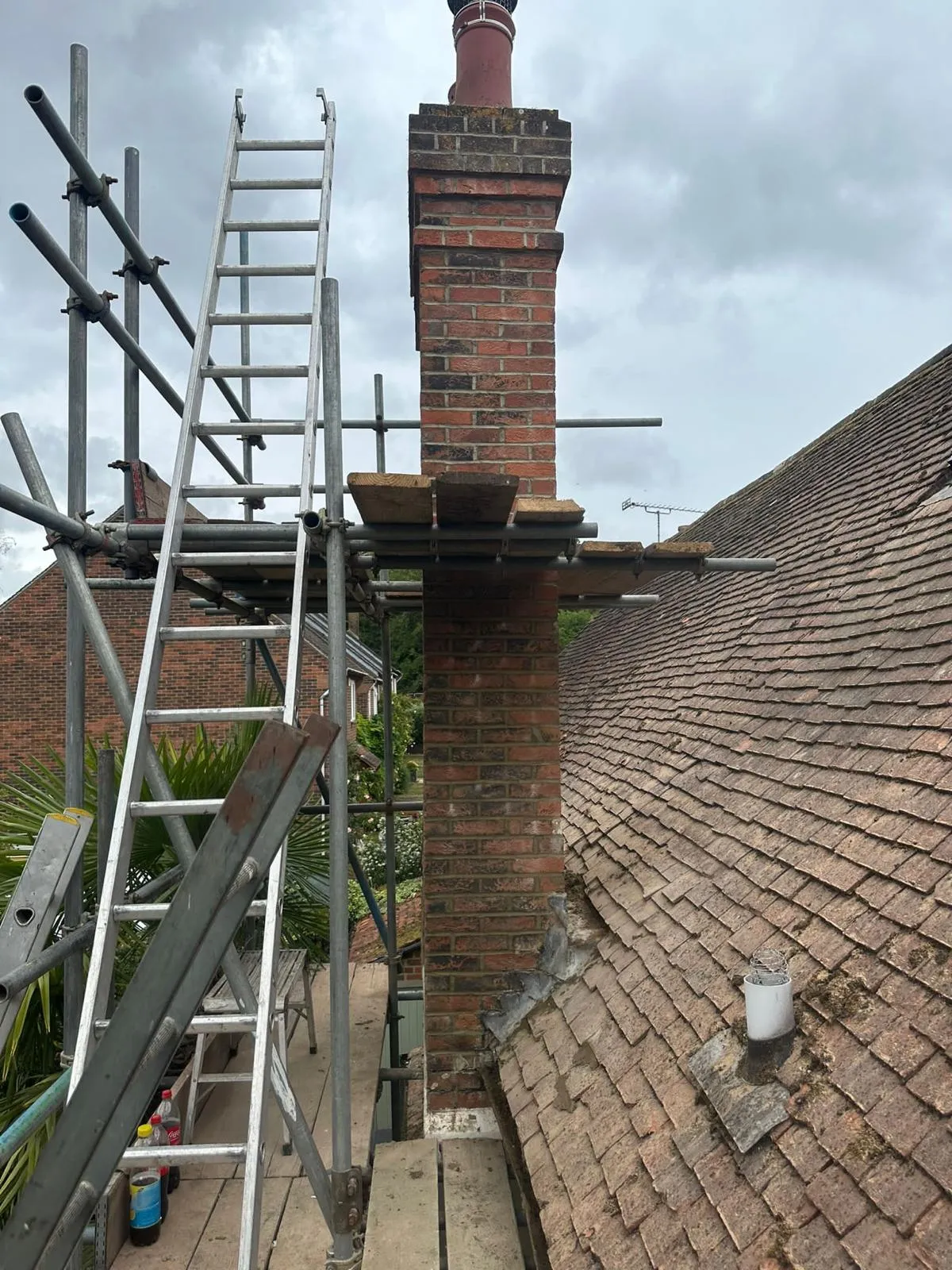 Scaffolding erected around a brick chimney on a tiled roof, ready for repairs or repointing.