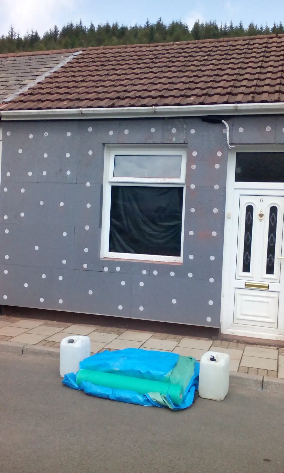 Grey EPS external wall insulation boards mechanically fixed to the exterior of a solid wall property in South Wales prior to rendering application.