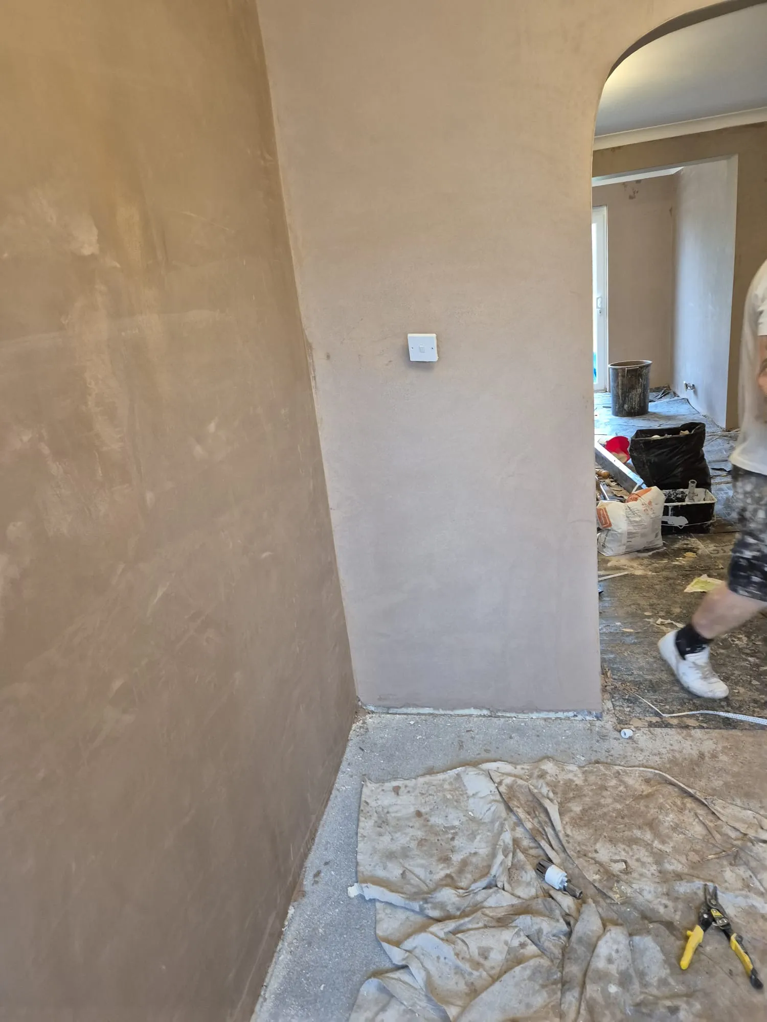 Freshly plastered walls and an arched opening in a room undergoing a home refurbishment.