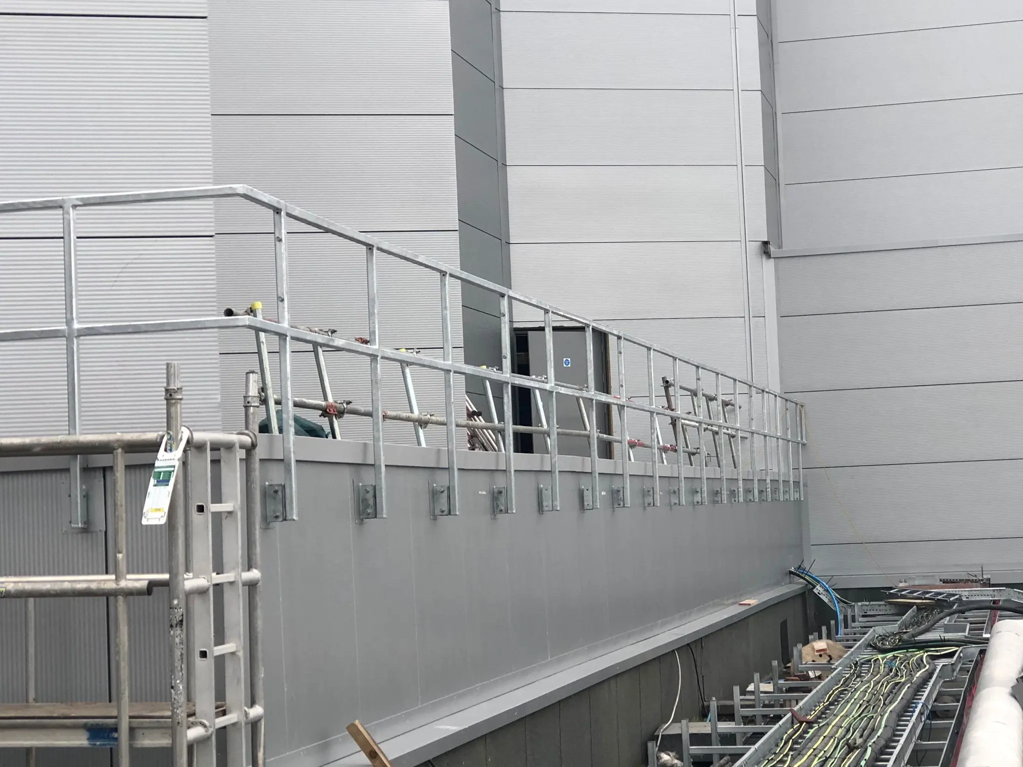 Grey weather-resistant cladding and galvanized safety railings installed on a commercial industrial unit by ER3 Group LTD