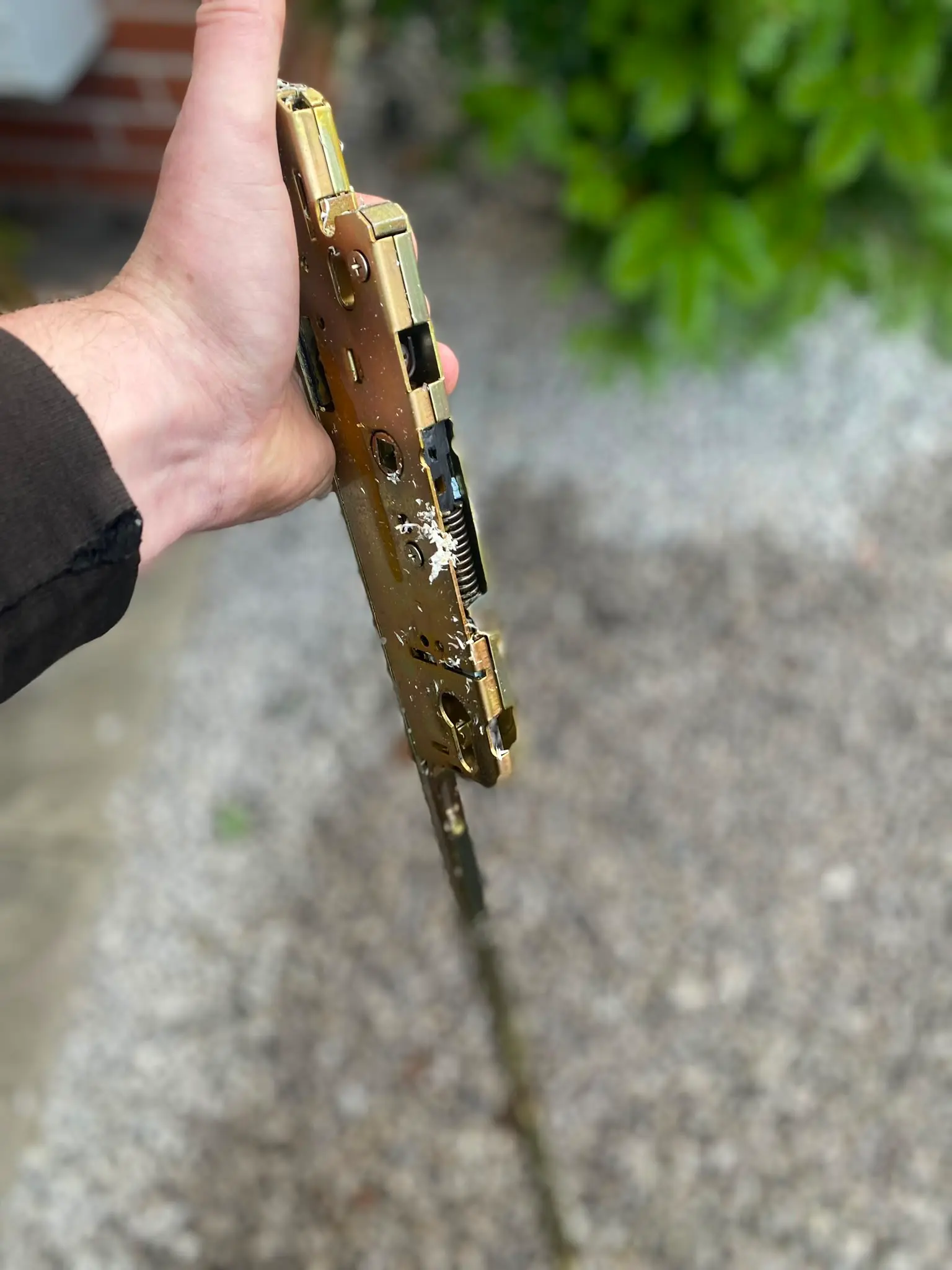 A locksmith holding a faulty multi-point lock mechanism during a uPVC door lock replacement