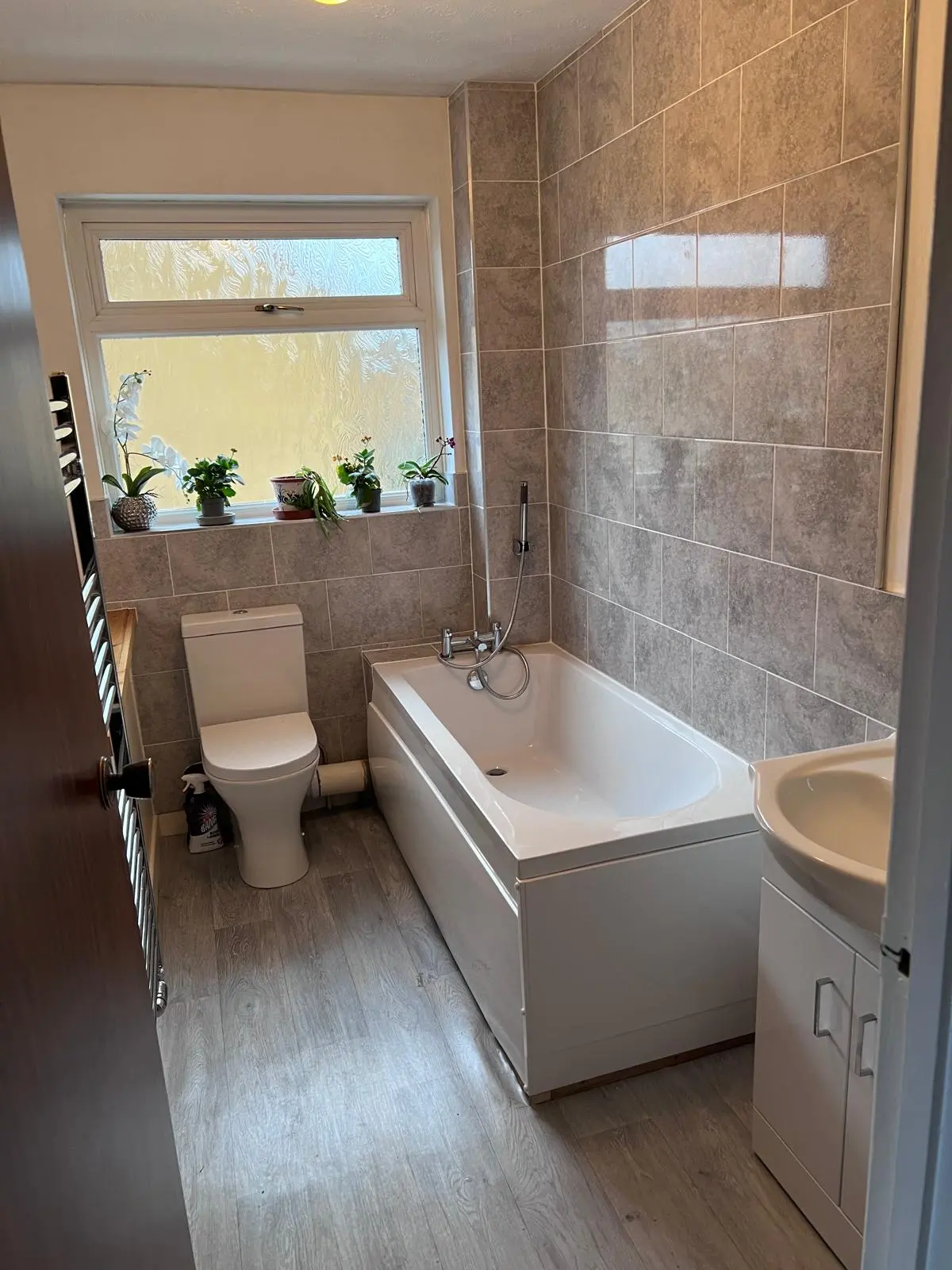 Modern bathroom plumbing and suite installation in Frome featuring grey tiling and white sanitaryware.