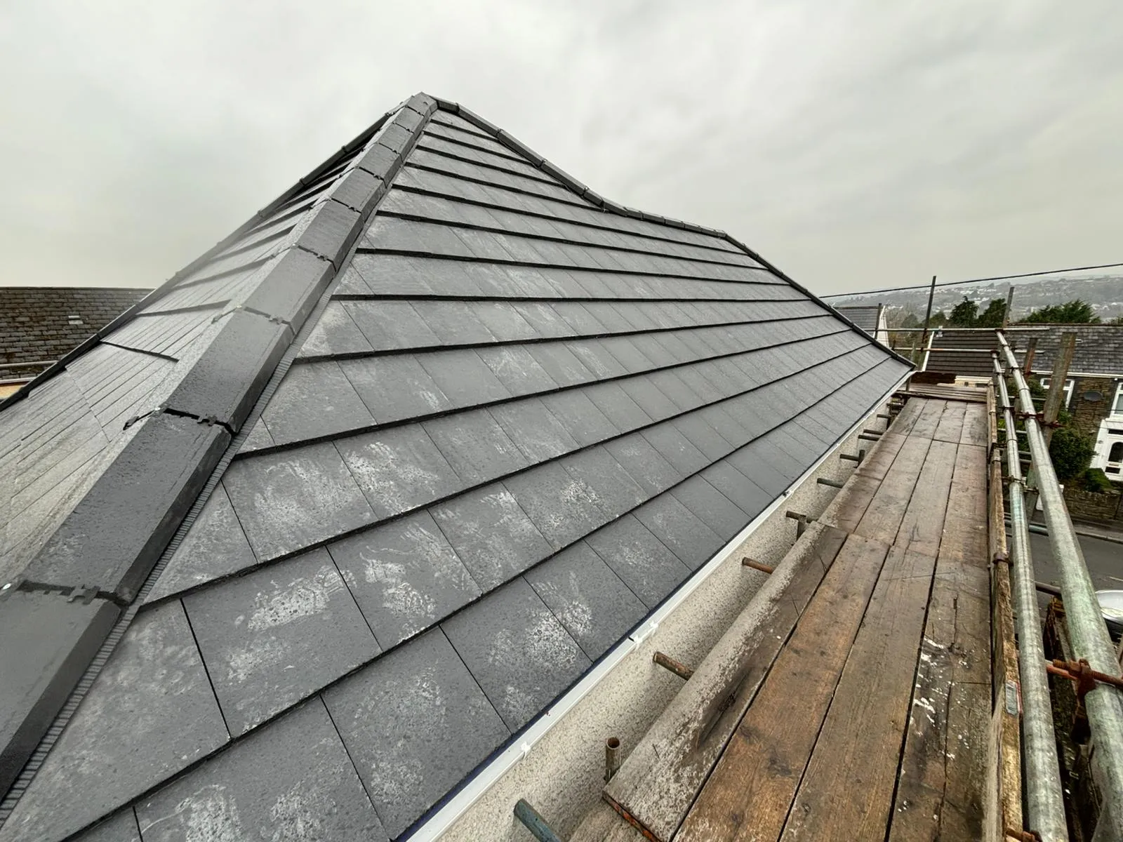 Professional installation of a dark grey tiled roof with a dry ridge system in Gloucestershire